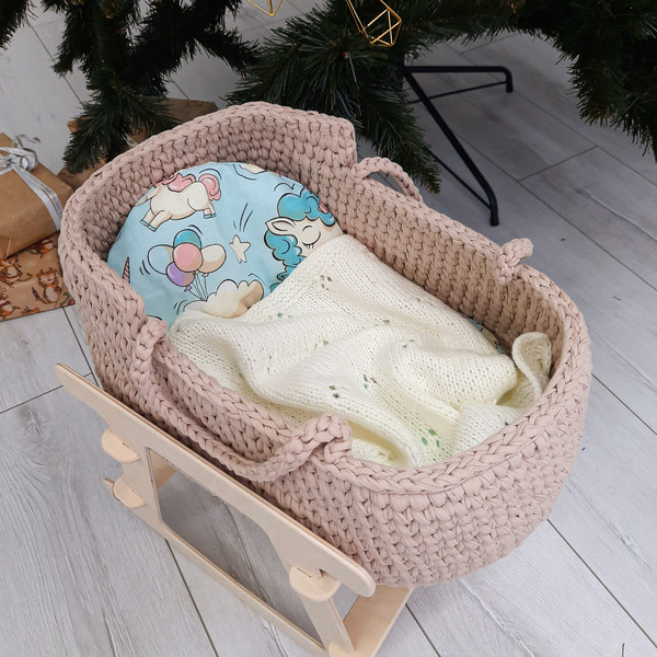 Basket for baby dolls in beige handmade on a wooden stand, with a cute bright mattress and a milk-white blanket
