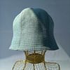 A bell hat made of linen fabric with a houndstooth print. Panama hat with a pied-de-poule print. Mint panama hat  tulip.