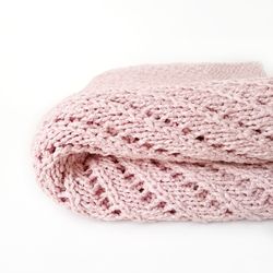 hand-knit pink baby blanket with delicate lace pattern and silky texture. perfect gift for newborns. handcrafted blanket