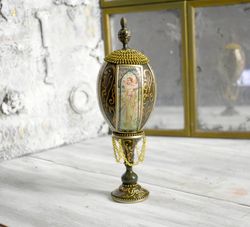 figurine-egg on a curly stand with the image of a painting by alphonse mucha