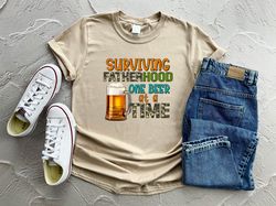 surviving fatherhood one beer at a time shirt cool and trendy dad shirt with a humorous twist on fatherhood funny dad sh