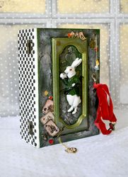 a green box with a white rabbit from alice a box for cards or jewerly