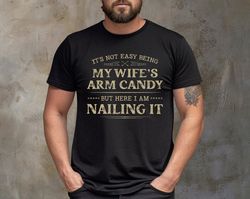 its not easy being my wifes arm candy t-shirt, funny shirt men - fathers day gift - husband - dad gi